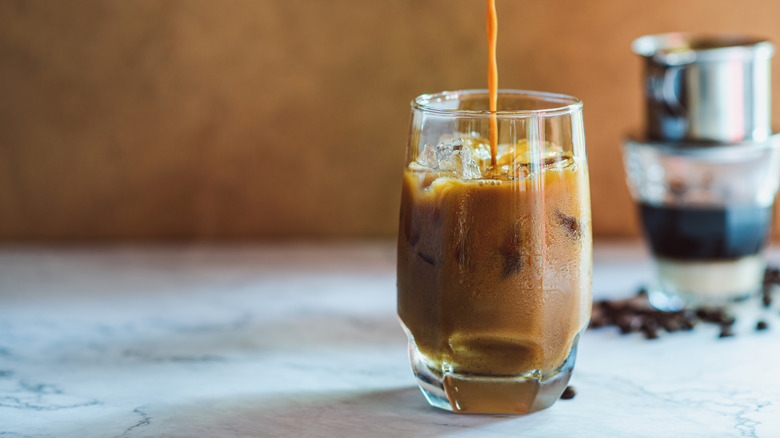 Iced Vietnamese coffee is poured into a glass.
