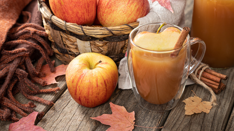 A mug of caramel apple cider in an autumnal tableau.
