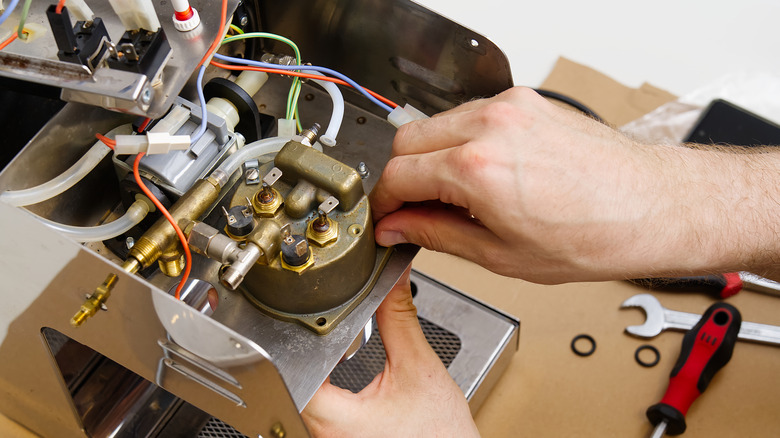 Person trying to repair a coffee machine