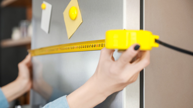 Person measuring a fridge in a store