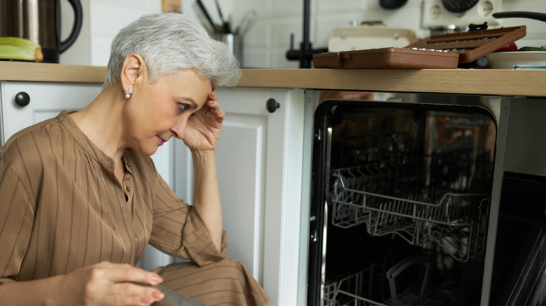Stressed person looking at a dishwasher