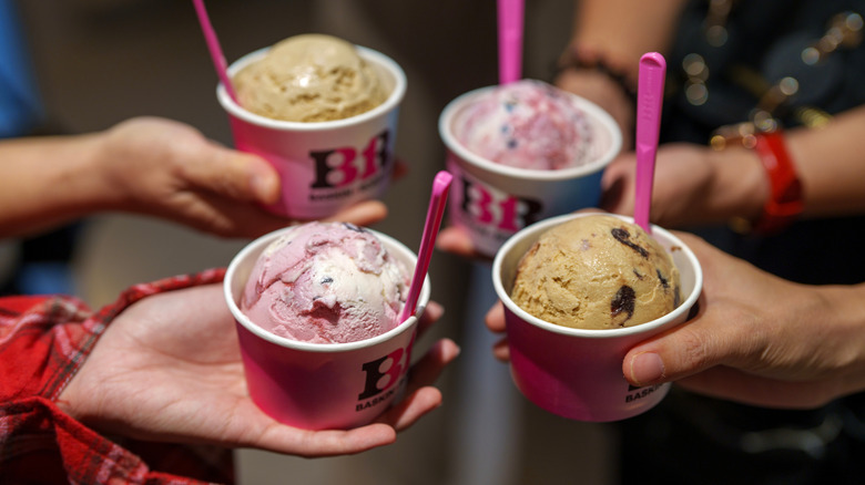 Hands holding cups of Baskin-Robbins ice cream