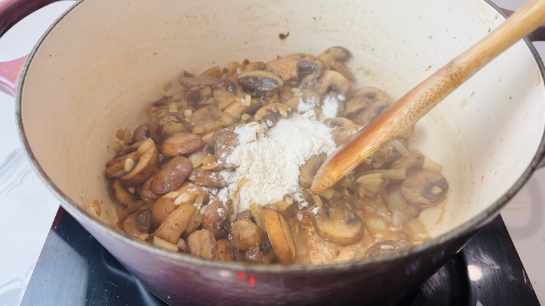 Mushrooms, flour, and wooden spoon in Dutch oven