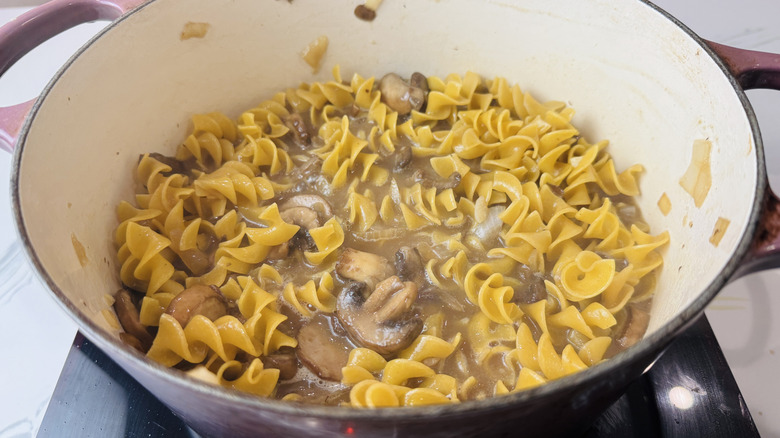 Egg noodles and mushrooms in broth mixture in Dutch oven