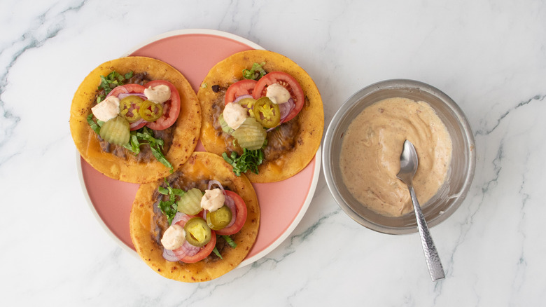 A plate with topped burger tacos dolloped with sauce