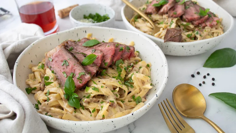 Elevated steak Alfredo served in two white bowls