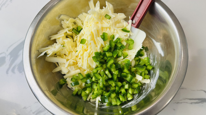 Diced jalapeño and shredded white cheddar cheese in bowl