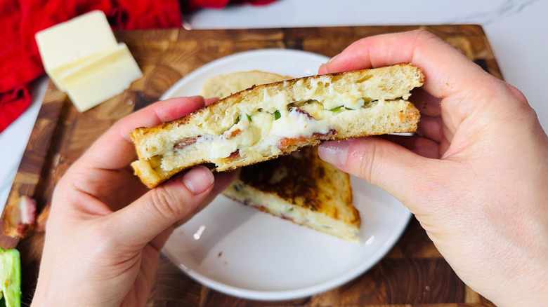 Hands holding jalapeño popper grilled cheese sandwich half