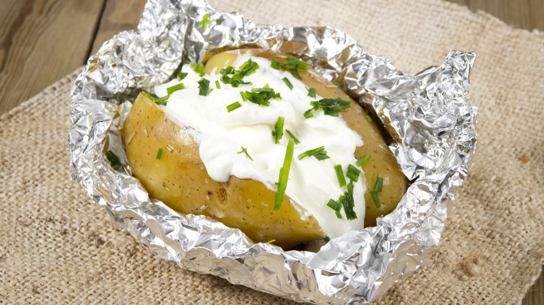 A baked potato with sour cream and chives.