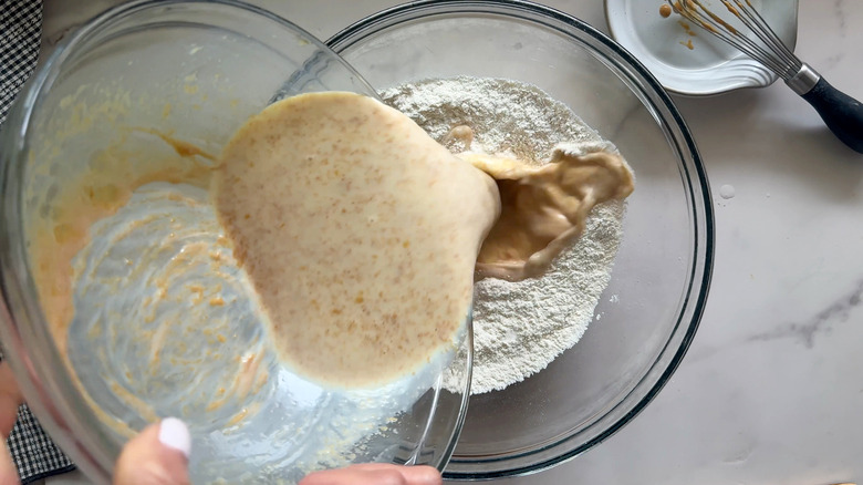 Peanut butter milk mixture pouring into bowl of flour