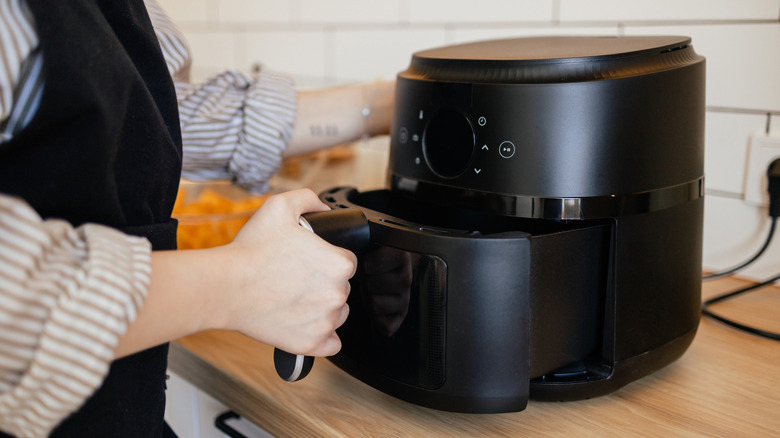 A person placing the detachable basket into an air fryer
