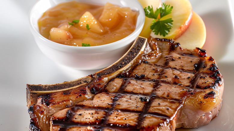 Grilled pork chop with sear marks and a side of applesauce