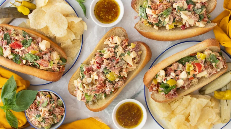 Chopped Italian sandwiches on a board with chips