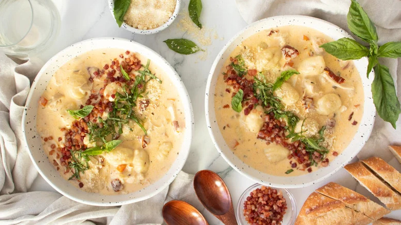 Bowls of soup on a table with herbs