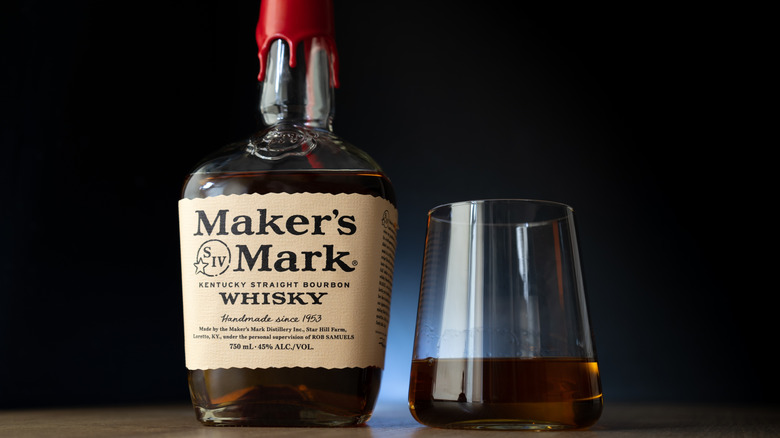 A bottle of Maker's Mark bourbon next to a glass of bourbon