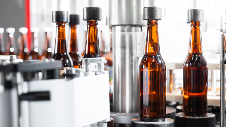 Glass beer bottles being capped in a factory