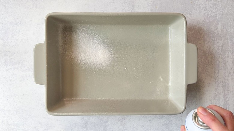 Spraying baking spray into a baking dish
