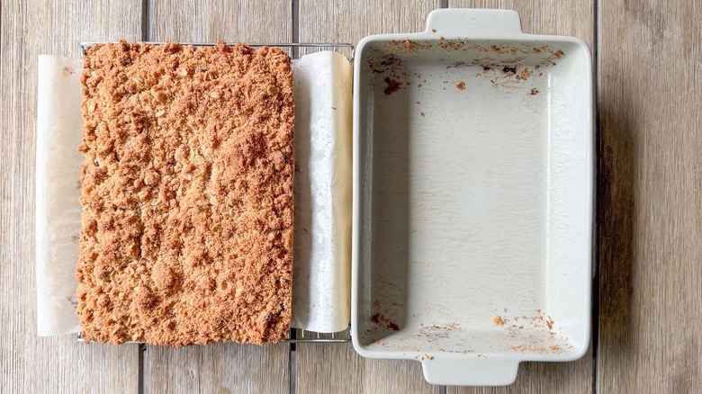 Old-fashioned blueberry crumb cake on parchment next to empty baking dish