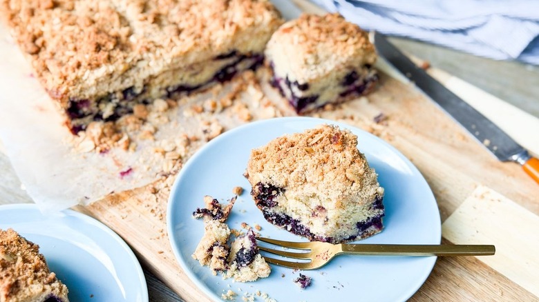 Slices of blueberry crumb cake on cutting board and blue plate