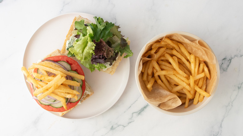 A burger topped with an assortment of veggies and fries