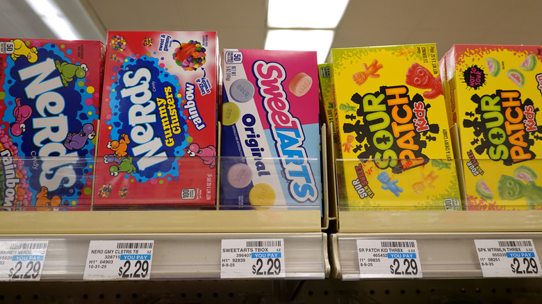A display of candy boxes on a store shelf with SweeTarts in the middle.