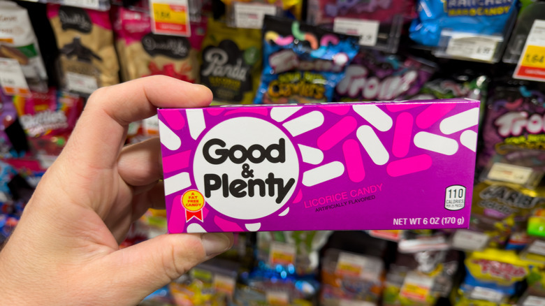 A hand holding a box of Good & Plenty candies.