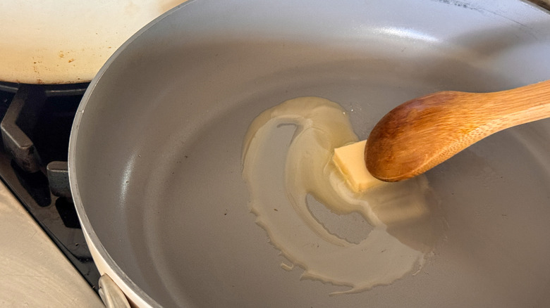 wooden spoon stirring butter in skillet