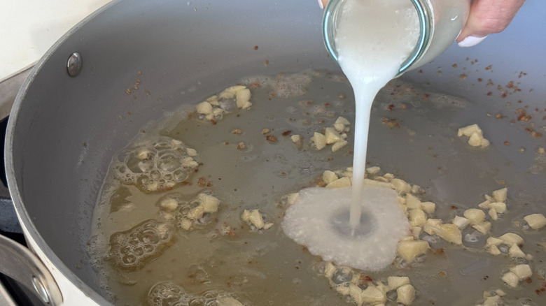 Cream pouring into pan with garlic