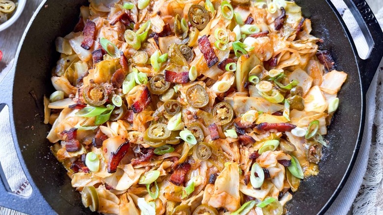 Closeup of skillet cowboy cabbage with jalapeño and scallion garnish
