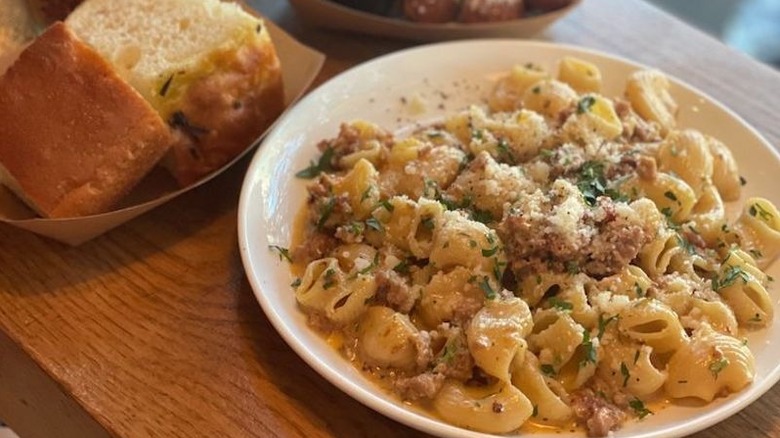 An order of pipette ragu from Forma Pasta Factory on a white plate alongside fresh focaccia bread