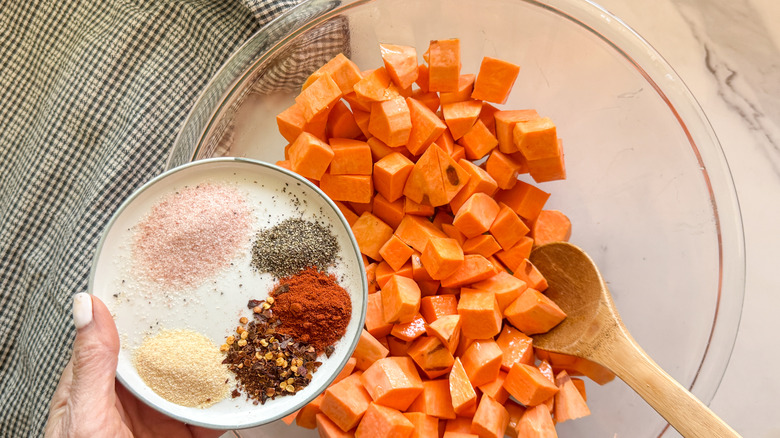 hand adding spices to bowl