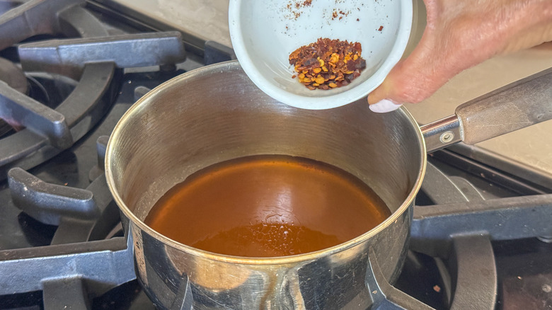 adding red pepper flakes to pot