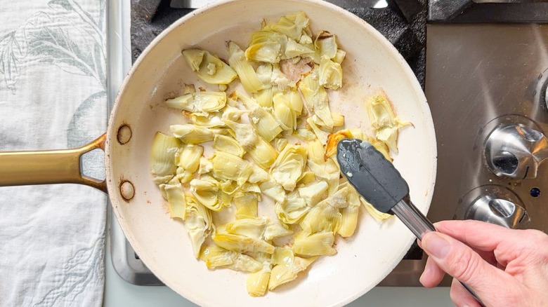 Artichoke heart quarters browning in skillet on stovetop