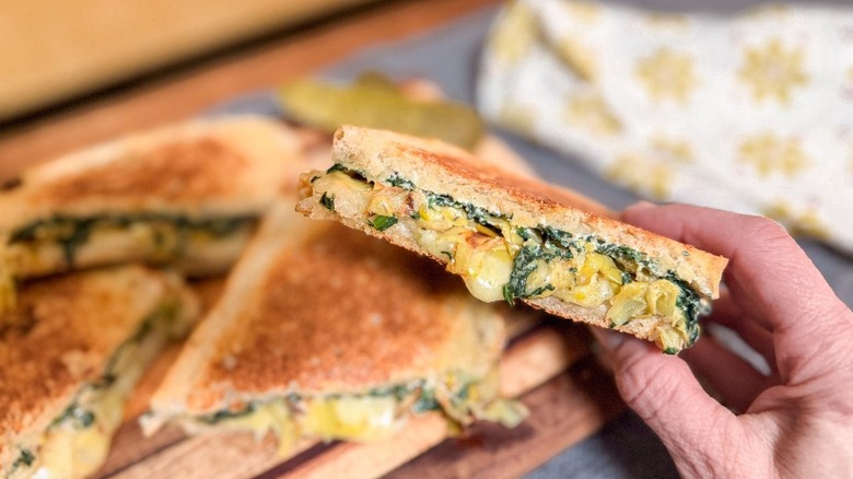 Close up of ultimate spinach artichoke grilled cheese half with melting cheese
