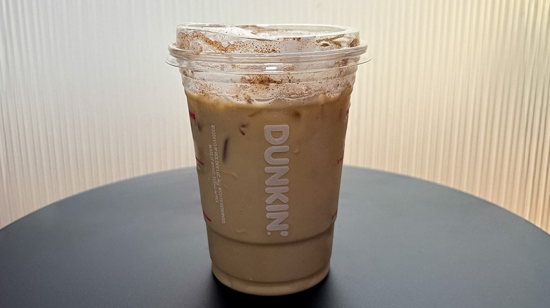 Small Dunkin' Pumpkin Spice Iced Signature Latte on a black table